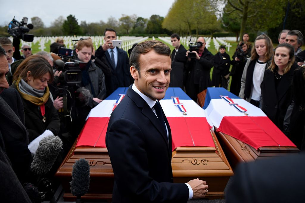 Image of a man standing in front of 2 coffins looking at the camera smiling.
