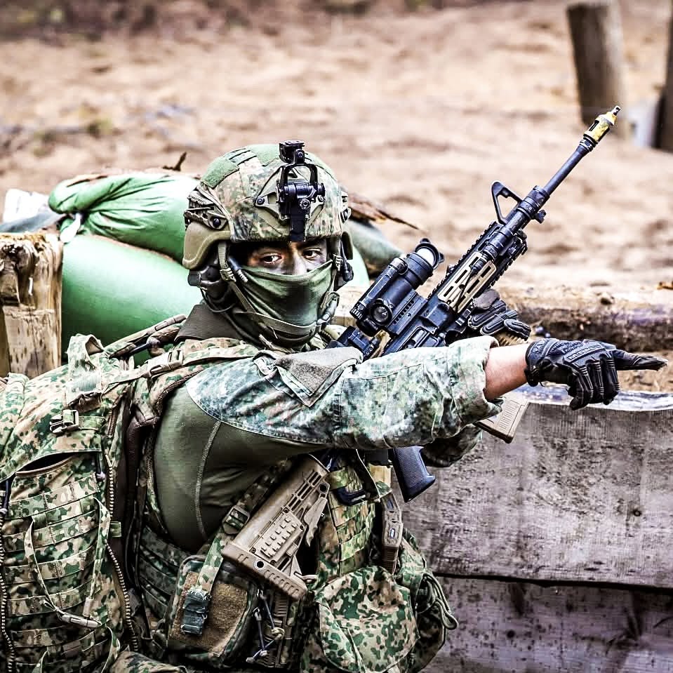 Soldier in trenches with uniform holding a weapon.