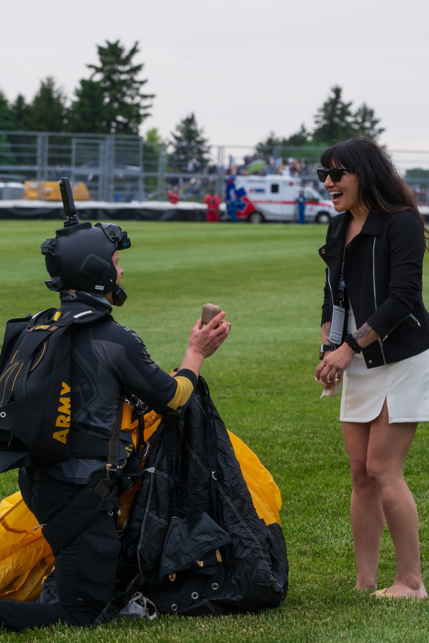 Skydiver after landing proposing to a woman on the ground.